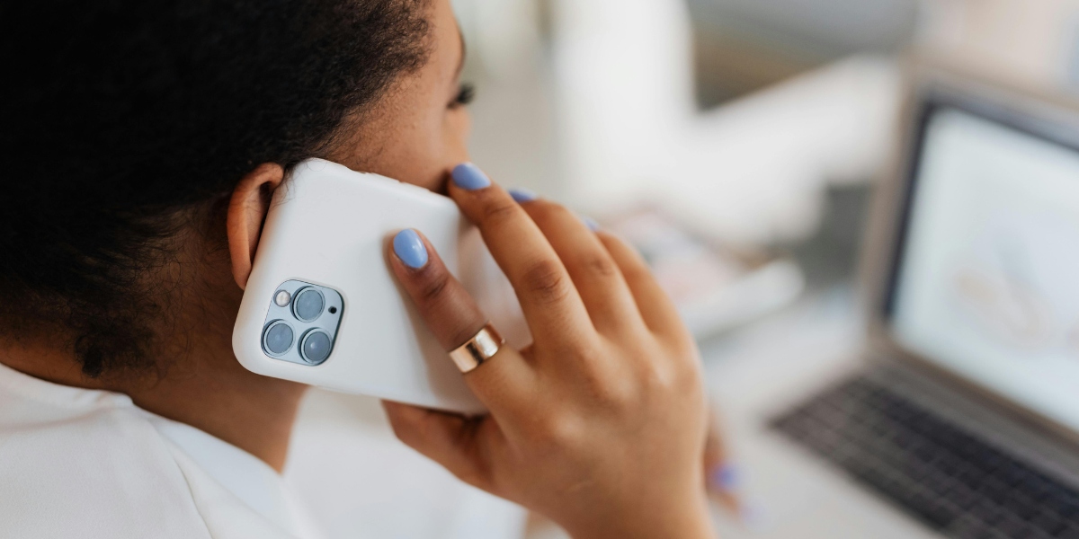 How to Protect Yourself from Storm-Damage Scams After Severe Weather 1 Close-up of a woman on the phone, calling for emergency help after storm damage, with a laptop open in front of her.