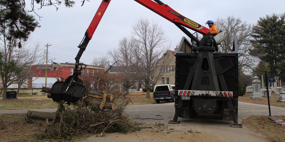 How to Protect Yourself from Storm-Damage Scams After Severe Weather 3 Grapple truck loading storm-damaged branches and logs into a debris truck during cleanup work.