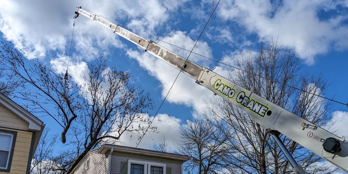 The Lefke Tree Experts crane lifting a tree out of a backyard during a tree removal job in Pendleton, OH.