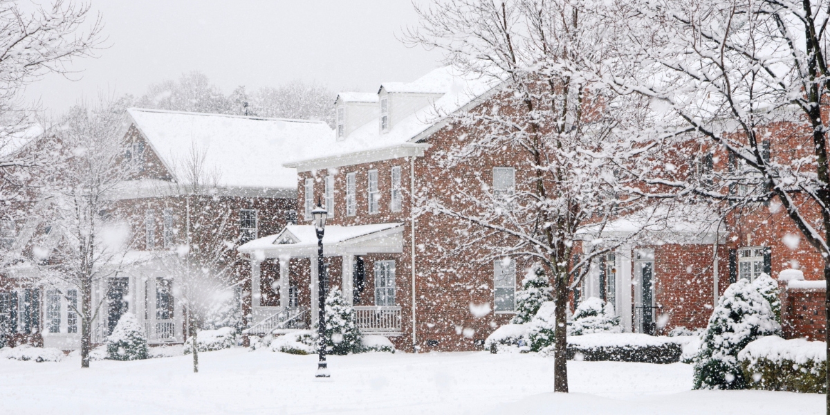 Winter Tree Work in Cincinnati: Why Smart Homeowners Get Estimates Now 2 Residential Cincinnati neighborhood covered in fresh snow with bare trees, brick homes, and a streetlamp during a winter storm.