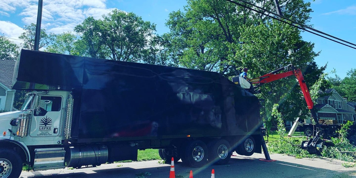 Lefke Tree Experts truck with aerial lift equipment working on tree removal in Cincinnati residential neighborhood with overhead utility lines.