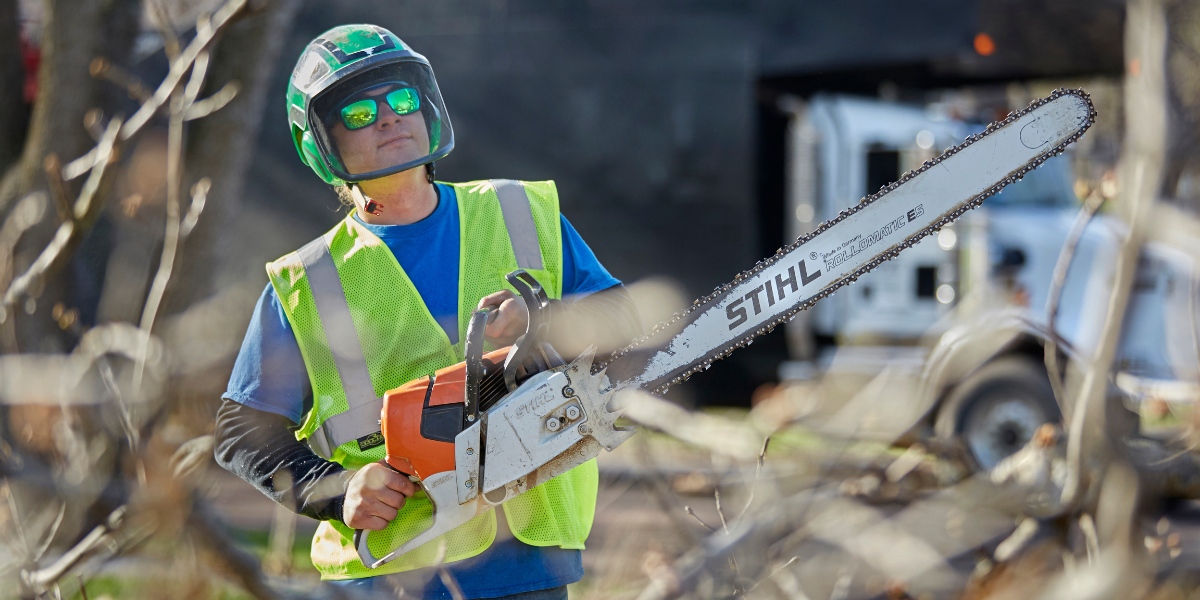 Certified Arborist from Lefke Tree Experts wearing full safety gear while performing proper professional tree pruning with chainsaw in Cincinnati.