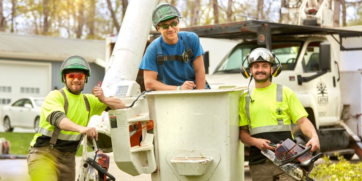 What to Expect with Large Tree Removal in Cincinnati 3 Three Lefke Tree Experts crew members in safety gear stand by a bucket truck holding chainsaws.