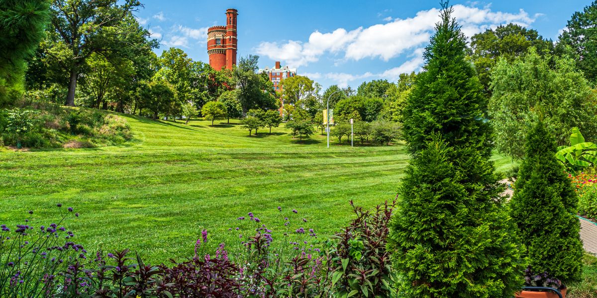 The view towards the standpipe in Eden Park, Cincinnati, Ohio, with green grass, with trees, shrubs, and flowers, demonstrating the benefits of trees.
