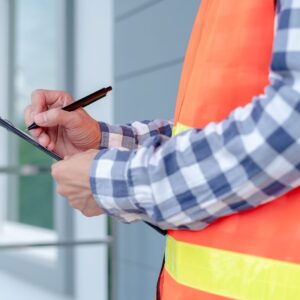 Close-up of a Lefke arborist in an orange safety vest and checkered shirt writing on a clipboard while inspecting a property for winter tree work in Cincinnati.